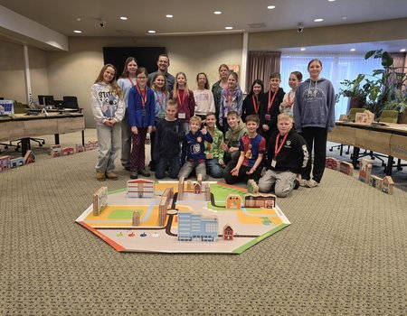 groep kinderen om het spelkleed Democracity een en de begeleiders van het spel