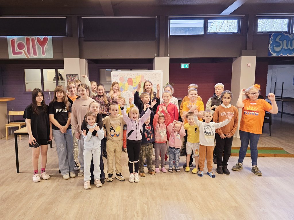 de kinderen uit de opvang en de kinderraadsleden poseren in de gezamenlijke ruimte voor de wereldkaart